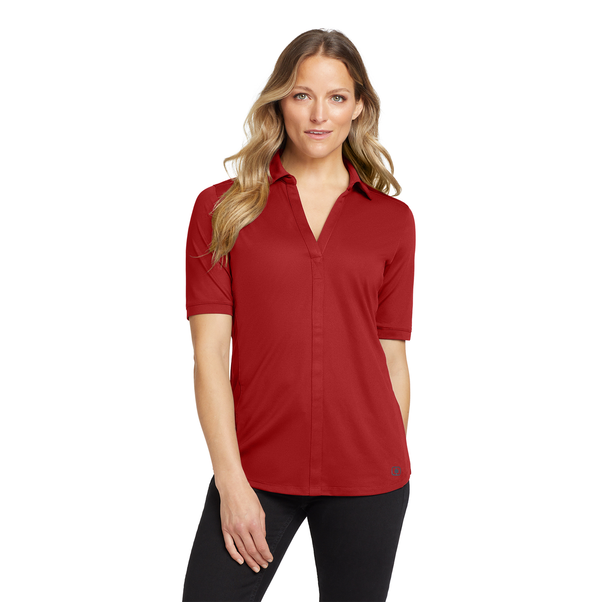 Portrait of a woman in a red blouse standing against a white studio background, facing the camera with a subtle smile.