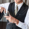 Person in a suit pours wine into a glass at a formal event (close-up on the hands)