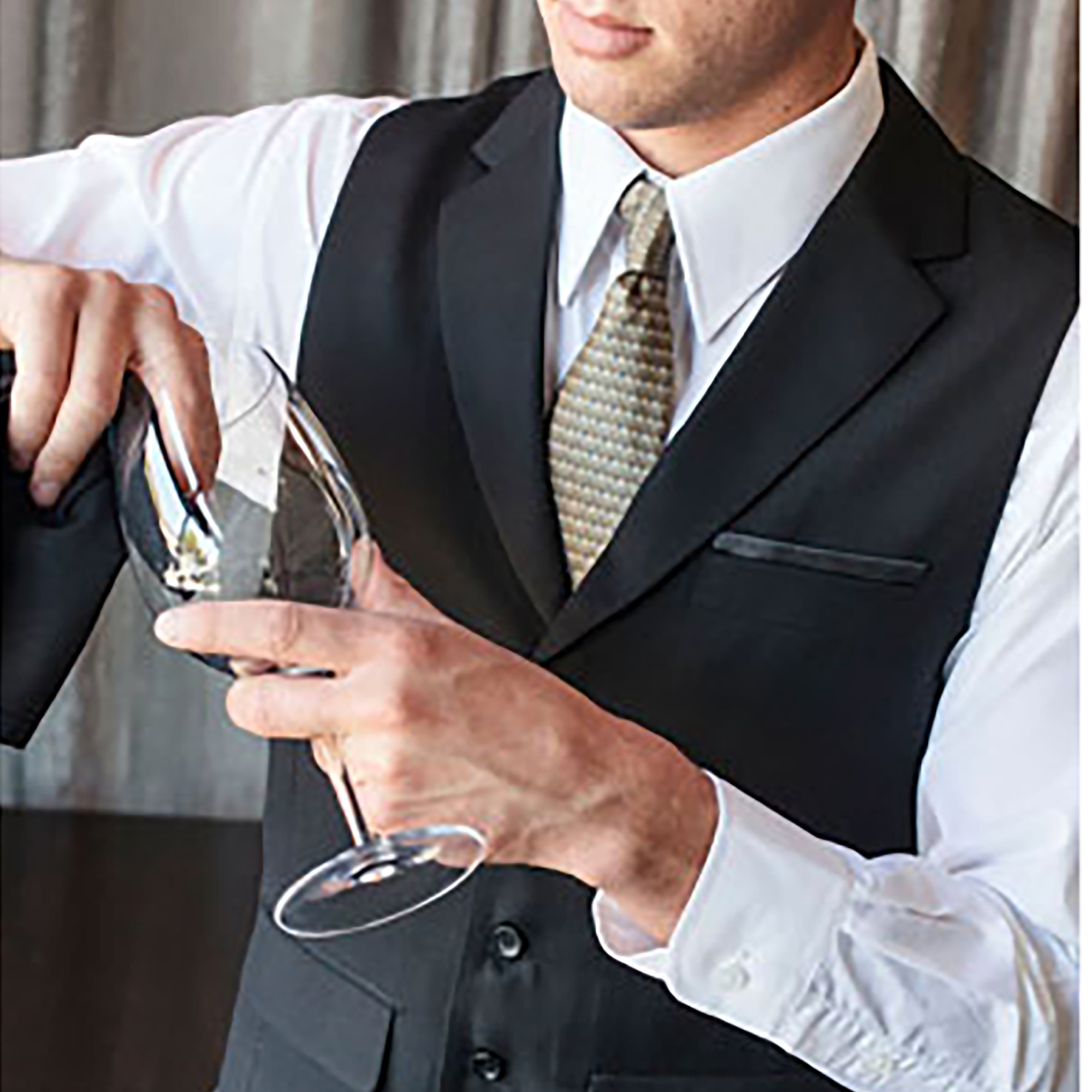 Person in a suit pours wine into a glass at a formal event (close-up on the hands)